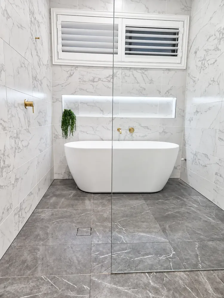 Panania main bathroom with freestanding bath, marble-look tiles and backlit shower niche