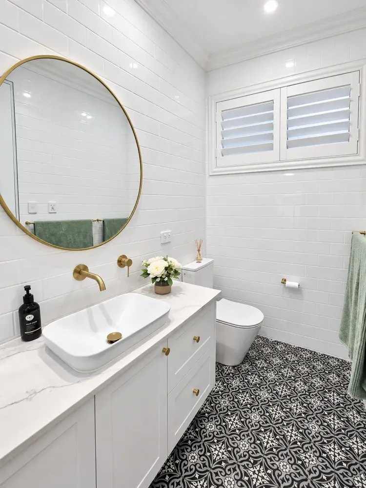 Panania bathroom with brass-framed round mirror, vessel basin and patterned floor tiles