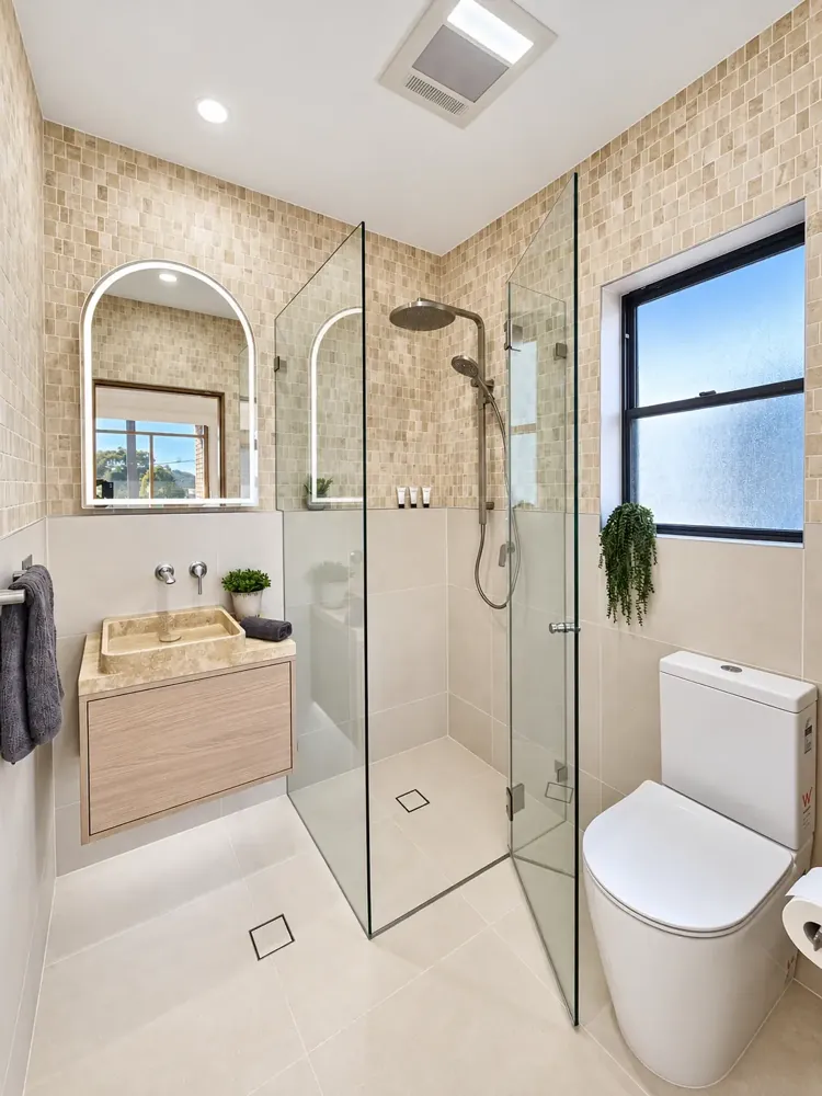 Sans Souci bathroom with arched LED mirror, stone basin and walk-in glass shower